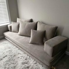 a couch sitting in front of a window on top of a white carpeted floor