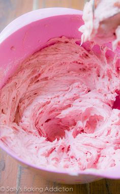 a pink bowl filled with ice cream on top of a wooden table