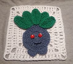 a crocheted square with a blue and green broccoli face on it