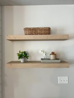 two wooden shelves with baskets and flowers on them in a bathroom area next to a toilet