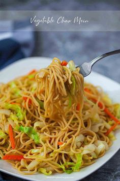 a spoon full of noodles and vegetables on a white plate