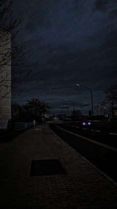 a dark city street at night with the lights on and no one in the distance