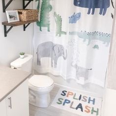 a bathroom with a shower curtain that has animals on it and the words splash splash