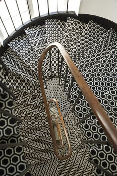 a spiral staircase with black and white tiles on the floor, along with wooden handrails