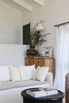 a living room with white couches and pillows on the floor next to a table