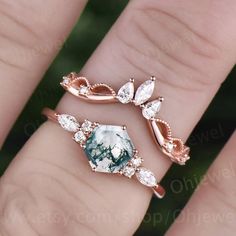 a woman's hand with two rings on it and one ring has an emerald stone