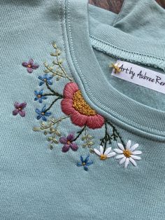 an embroidered t - shirt with daisies and flowers on the front, along with a name tag