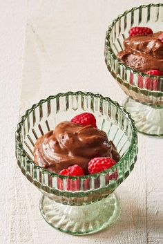 two small glass bowls with chocolate pudding and raspberries in them on a table