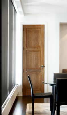 a dining room table and chairs in front of a wooden door