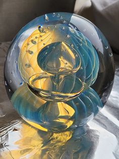 a glass vase sitting on top of a table next to a couch with pillows in the background