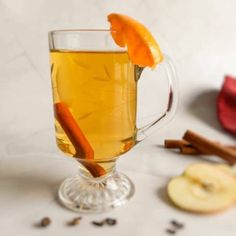 a glass mug filled with apple cider and cinnamon sticks