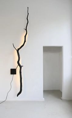 a black tree branch on the wall next to a white room with an electrical outlet