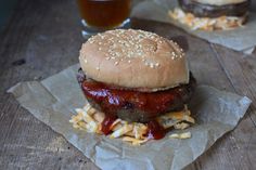 two hamburgers with cheese and ketchup on them next to a glass of beer