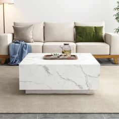 a white marble coffee table sitting on top of a carpeted floor next to a couch