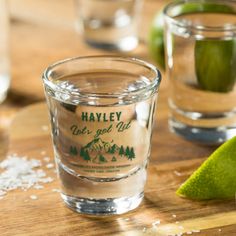 a wooden table topped with glasses filled with water and limes next to each other