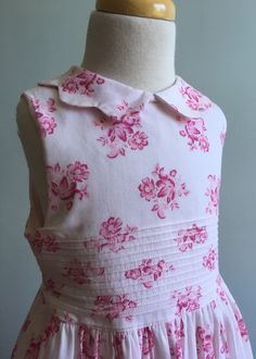 "Another classic from Laura Ashley, this dress is made from a cotton that is finely ribbed and printed with vintage looking bouquets of flowers. The ground is a very pale pink while the florals are rendered in pink and a rosy red. The front bodice features a 3.25\" band of tucks and a similar band is on lower skirt. (This is hard to see in photos.). Skirt is long, gathered and full, both front and back. The collar is what I call a \"piecrust\"; the outer edge is scalloped. Dress is sleeveless wi Feminine Pink Sleeveless Dress For Garden Party, Pink Fitted Sleeveless Dress For Garden Party, Fitted Pink Sleeveless Dress For Garden Party, Pink Cotton Sleeveless Dress For Garden Party, Sleeveless Fitted Cotton Floral Dress, Sleeveless Fitted Floral Cotton Dress, Fitted Sleeveless Cotton Floral Dress, Pink Fitted Sleeveless Cute Dress, Cute Fitted Pink Sleeveless Dress