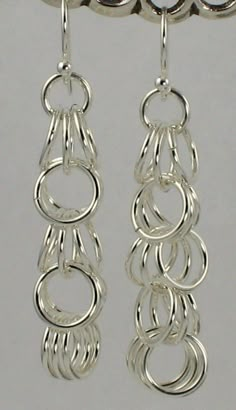 two pairs of silver earrings hanging from hooks