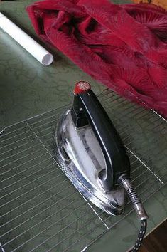 an iron is sitting on top of a table next to a red blanket and pen