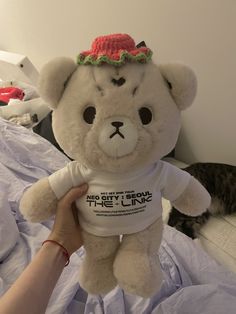 a white teddy bear with a red hat on it's head sitting on a bed