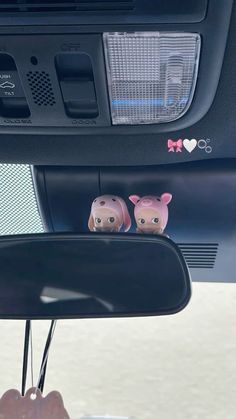 two little pigs are sitting on the dash board of a car with its rear view mirror