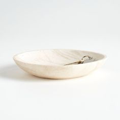 a white bowl sitting on top of a table next to a pair of tongs