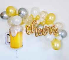 a beer and balloons with the word cheers spelled out in gold, silver, and white