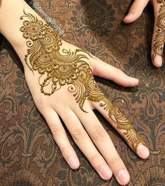 two hands with henna tattoos on them, one is showing off the intricate design