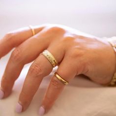 a woman's hand with two gold rings on it