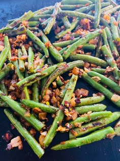 cooked green beans with bacon and seasonings on a black plate, ready to be eaten