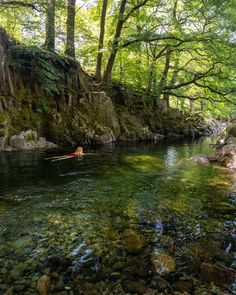 a person in a kayak paddling down a river surrounded by rocks and trees