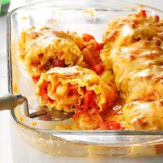 a glass casserole dish filled with lasagna covered in cheese and tomatoes