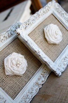 two white framed pictures with flowers and pearls on the top, sitting on a table