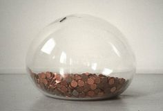 a glass bowl filled with coins on top of a table next to a white wall