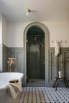 a bathroom with a black and white tile floor, an arched window, and a bathtub