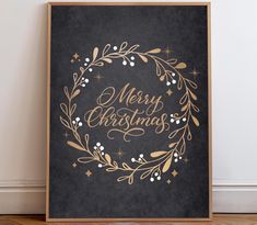 a black and gold merry christmas sign on a wooden frame next to a white wall