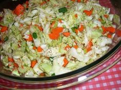 a bowl filled with coleslaw and carrots on top of a checkered table cloth