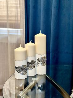 three candles sitting on top of a glass table