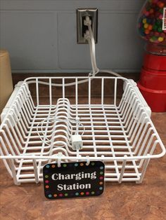 a white wire basket sitting on top of a wooden table next to a sign that says charging station