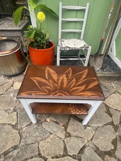 a wooden table sitting on top of a stone floor next to a potted plant