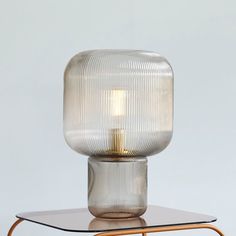 a glass table lamp sitting on top of a metal stand with a light bulb in the middle