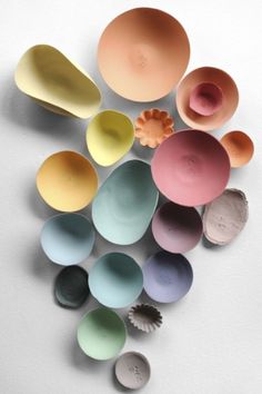 many different colored bowls and spoons on a white surface