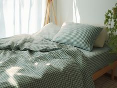 a bed with green and white checkered sheets in a room next to a window