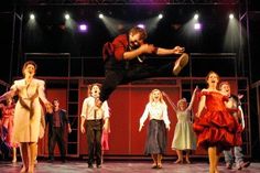 a group of people standing on top of a stage with one person jumping in the air