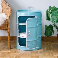 a blue metal barrel sitting on top of a hard wood floor next to a chair