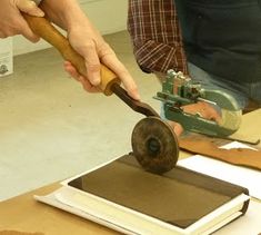 a person using a wood plane to cut paper