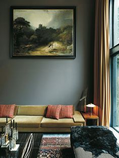 a living room filled with furniture and a painting hanging on the wall above it's windows