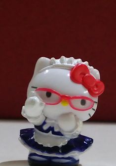 a hello kitty figurine with red glasses and a bow on her head sitting on a table