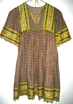 Amazing vintage dress in an ethnic hippie style, has trims and rick rack at neck, bodice, sleeves and hem. Dress is not marked and has no size label, please go by measurements for best results. Perfect for x small adult, condition is good with 2 small areas that can be repaired at top of shoulder. Fabric is a beautiful semi sheer soft cotton with a small raised stitch or weave. Any questions just convo. Thanks!! Across shoulders 11 inches Across bust 14 inches Across waist 14 inches Total length Bohemian V-neck Dress With Crochet Trim, Fitted V-neck Peasant Dress, Brown Hippie Boho Dress For Spring, Peasant Style V-neck Festival Dress, Fall Festival Bohemian Boho Dress, Fall Festival Bohemian Dress, Flowy Boho Dress With Lace Trim For Festival, Folk Style Tunic Dress For Fall, Spring Festival Brown Boho Dress