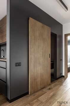 an open door in the middle of a room with wood floors and black painted walls