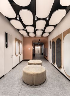 an empty hallway with several round mirrors on the wall and two stools in the middle